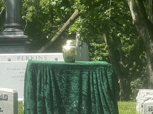 Urn on table during outdoor burial service amongst beautiful trees